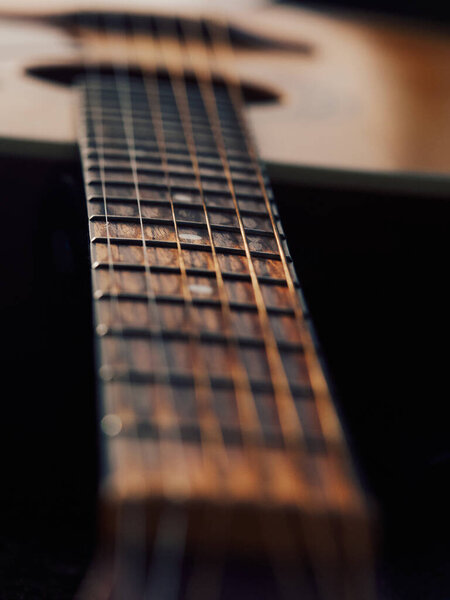 Теплый тонированный гитарный выстрел с мягким солнечным светом, фокус на шеи на переднем плане, размытое тело в небольшом наклоне в фоновом режиме, тонкие тени на шее, уютная и минимальная музыкальная композиция, художественное макро чувствовать.