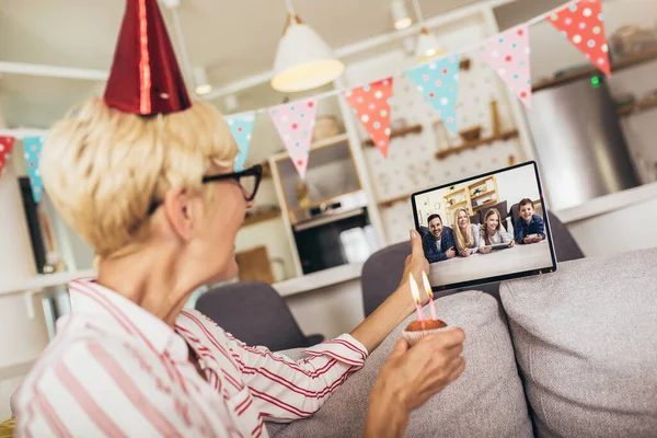 Senior woman alone at home having a celebration on a video call