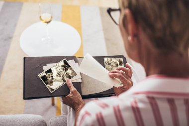 Neşeli, son sınıf öğrencisi, elinde aile fotoğrafı albümüyle evdeki kanepede oturuyor.