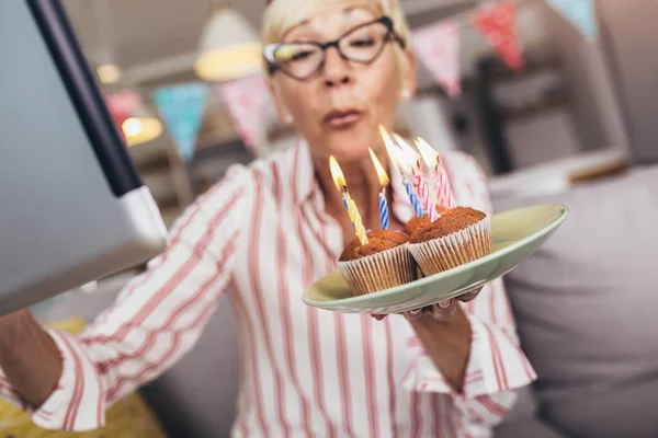 Senior woman alone at home having a celebration on a video call