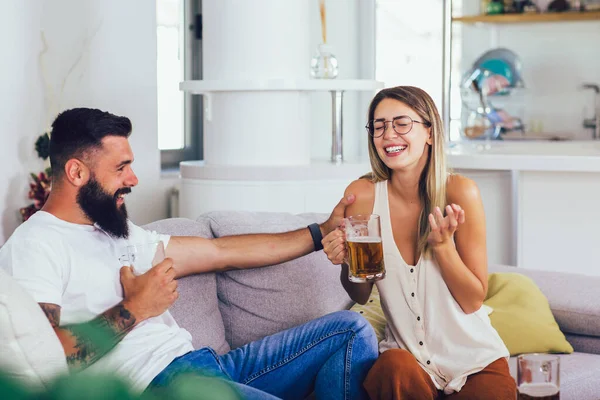 若い幸せなカップル通信しながら ソファに座ってビールを飲む — ストック写真