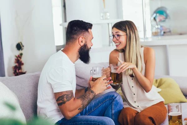 若い幸せなカップル通信しながら ソファに座ってビールを飲む — ストック写真