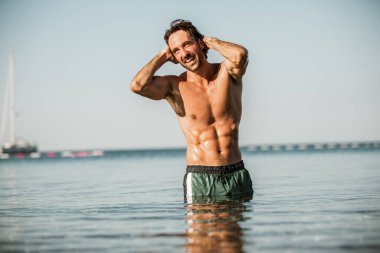 Deniz kenarında poz veren yakışıklı genç adam.