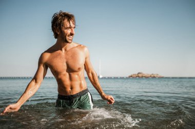 Deniz kenarında poz veren yakışıklı genç adam.