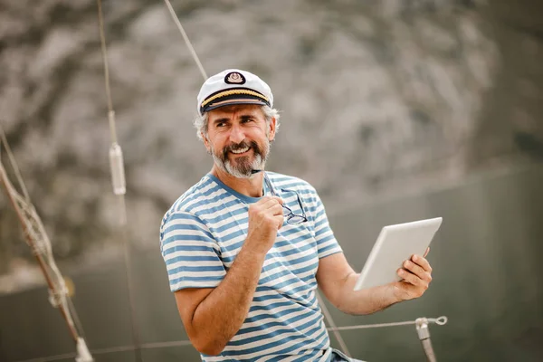 成熟した男立っていますで船の舵で海でデジタルタブレットを使用して晴れた日の午後 — ストック写真