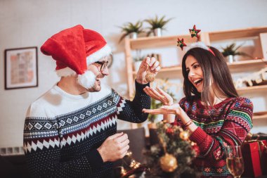 Yılbaşı gecesi evde Noel ağacı süsleyen çift.