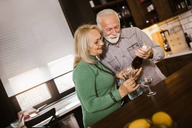 Yaşlı çift mutfakta şarap seçiyor..