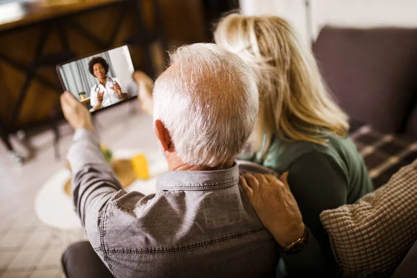 Seniorpar Hjemme Med Digital Nettbrett Videosamtale Med Familielege – stockfoto
