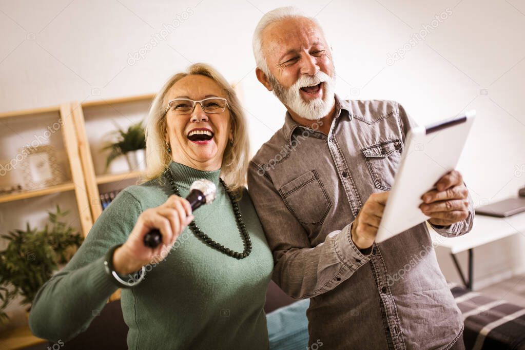 Senior couple singing karaoke at home, having fun.