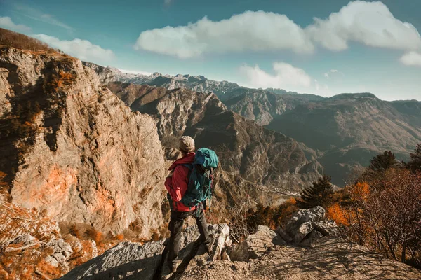 崖の端に立っていると山を見てバックパックを持つハイカーの男 — ストック写真