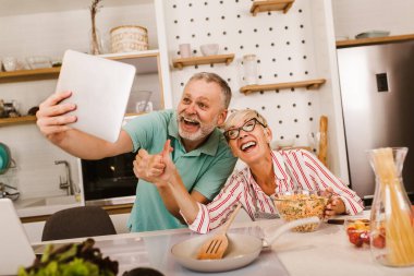 Yaşlı çift mutfakta yemek hazırlıyor, eğleniyorlar..
