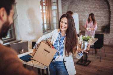 Kadının ilk iş günü modern ofise giriyor, kişisel eşyalarıyla uğraşıyor..