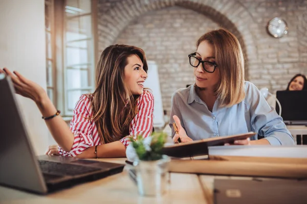 Team work process. Two women with laptop in open space office.