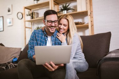 Mutlu çift evde dizüstü bilgisayar kullanırken iletişim kuruyor..