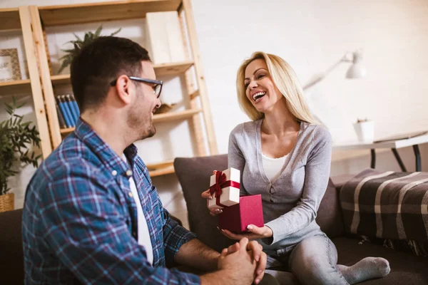 Young woman receiving a surprise gift box from her boyfriend at home.