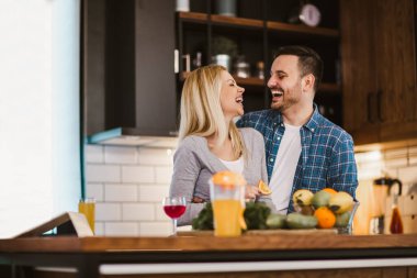Güzel genç çift evde mutfakta sağlıklı yemekler pişirirken konuşuyor ve gülümsüyor..