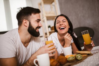 Yatak odasında kahvaltı yapan tatlı bir çift.