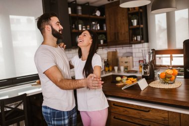 Neşeli çift sabahları mutfakta dans ederken eğleniyor.