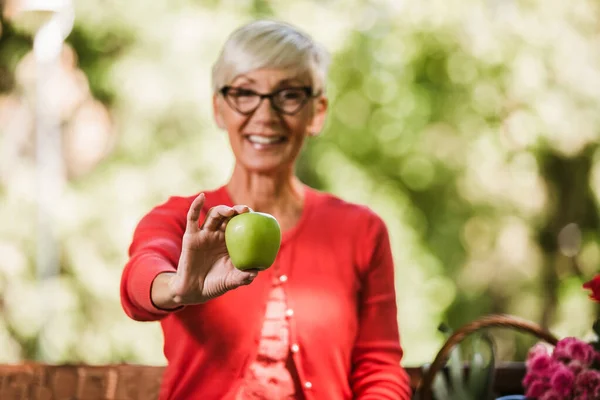 Zdrowo Wyglądająca Starsza Pani Siwymi Włosami Trzymająca Jabłko Zewnątrz Parku — Zdjęcie stockowe