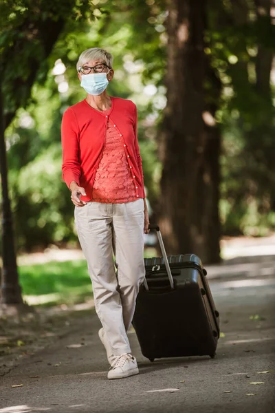 Seniorin Mit Schutzmaske Zieht Koffer Auf Reise — Stockfoto