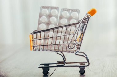 Alışveriş arabası ahşap masada, tabletlerde ve kredi kartında.