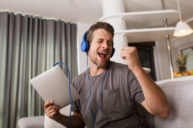 Yakışıklı genç adam koltuğunda oturup müzik dinliyor.