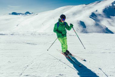 Genç sporcu serbest stil kayakçı kış mevsiminde güneşli bir günde tepeden aşağıya doğru koşarken eğleniyor.