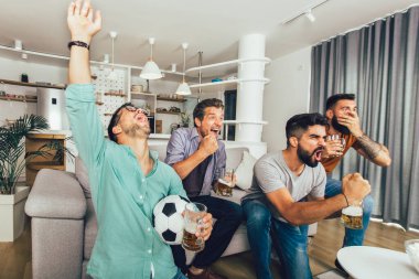 Mutlu erkek arkadaşlar ya da futbol taraftarları televizyonda futbol izleyip zaferi evde kutluyorlar..