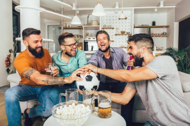 Vuvuzela 'lı mutlu erkek arkadaşlar siyah yüz koruyucu maske takıp evde futbol izliyorlar.