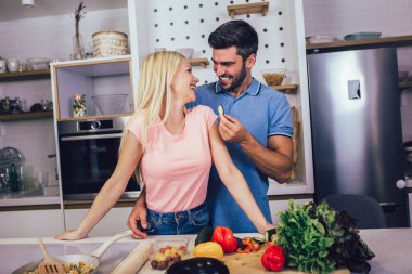 Evde sağlıklı yemekler pişirirken gülümseyen genç çift..