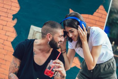 Kulaklıklı mutlu çift kafeteryada müzik paylaşıyor.