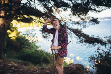 Olgun bir adam, deniz kenarında yürüyüş yapıyor ve doğayı keşfediyor.