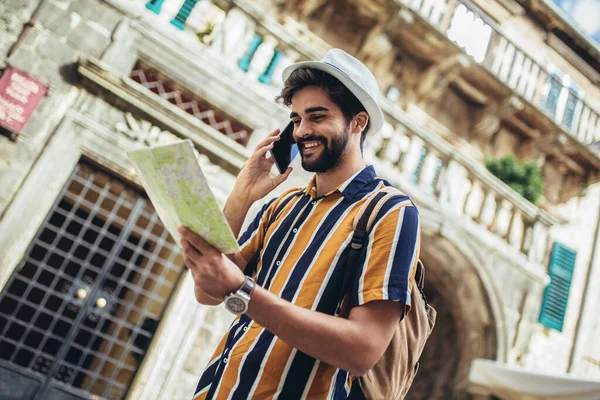 バックパック付きの幸せな観光客は 都市間の旅行をオリエンテーションのための地図を使用しています — ストック写真