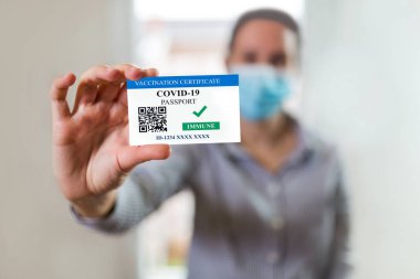 Aşı, hastalık dokunulmazlığı pasaportu, sağlık ve gözetim konseptleri. Kadının elinde COVID-19 için geçerli bir aşı belgesi var..