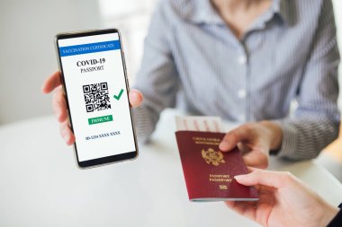 Otele yerleşmek ve pasaport geçirmek. COVID-19 için geçerli bir dijital aşı sertifikası gösteren akıllı telefon. Sahte QR