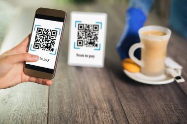 Kadın elleri kahve parasını ödemek için QR kodunu tarıyor. İndirim için tarama yap ya da kahve parasını öde. Para transferi için telefon kullanma ya da nakit olmadan internet üzerinden para ödeme kavramı..