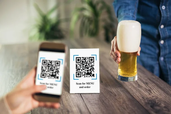 Women's hands are using the phone to scan the qr code to select menu. Scan to get discounts or pay for beer. The concept of using a phone to transfer money or paying money online without cash.