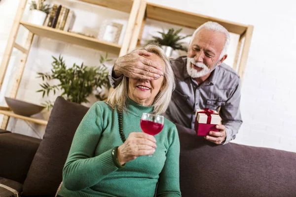 Senior man giving a present to his woman at home.