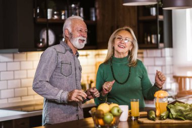 Üst düzey bir çift mutfakta birlikte yemek hazırlarken eğleniyor.