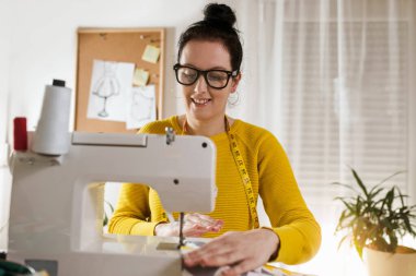 Evinde dikiş makinesine dikiş diken bir kadın. Dikiş makinesinde kadın terzilik işi