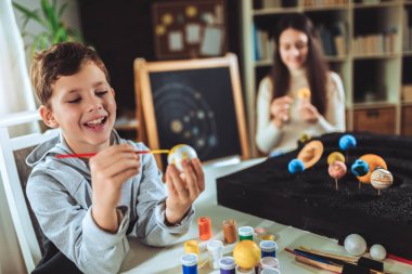 Mutlu okul çocuğu ve kız evde bir okul fen projesi için güneş sistemi yapıyorlar.