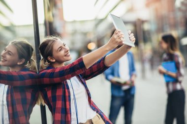 Dijital tablet kullanan mutlu üniversite öğrencisi arkadaşlar