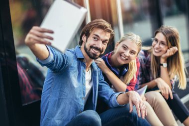 Bir grup arkadaş tabletle selfie çekiyorlar.