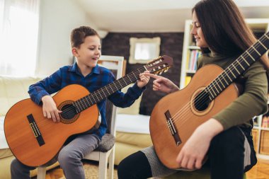 Erkek ve kız kardeş evde gitar çalıp eğleniyorlar..