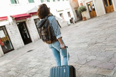  Avrupa 'nın eski şehrinde bavuluyla sokakta yürüyen bir kadın turist..