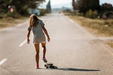 Genç sporcu kadın yolda kaykayla geziyor..