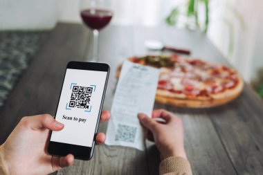 Kadınların elleri telefonu pizza ödemek için QR kodunu taramak için kullanıyor. İndirim için tarama yap ya da pizza için ödeme yap. Sahte QRQR kodları / barkodları olmadan para transferi veya çevrimiçi para ödemek için telefon kullanma kavramı saldırgan la içermez