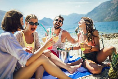 Genç arkadaşlar güneşli bir günde sahilde eğleniyorlar. Parti zamanı.