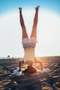 Genç bir kadın denizin arka planında yoga yapıyor..