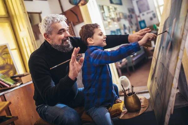 Father and son working and painting together in art studio